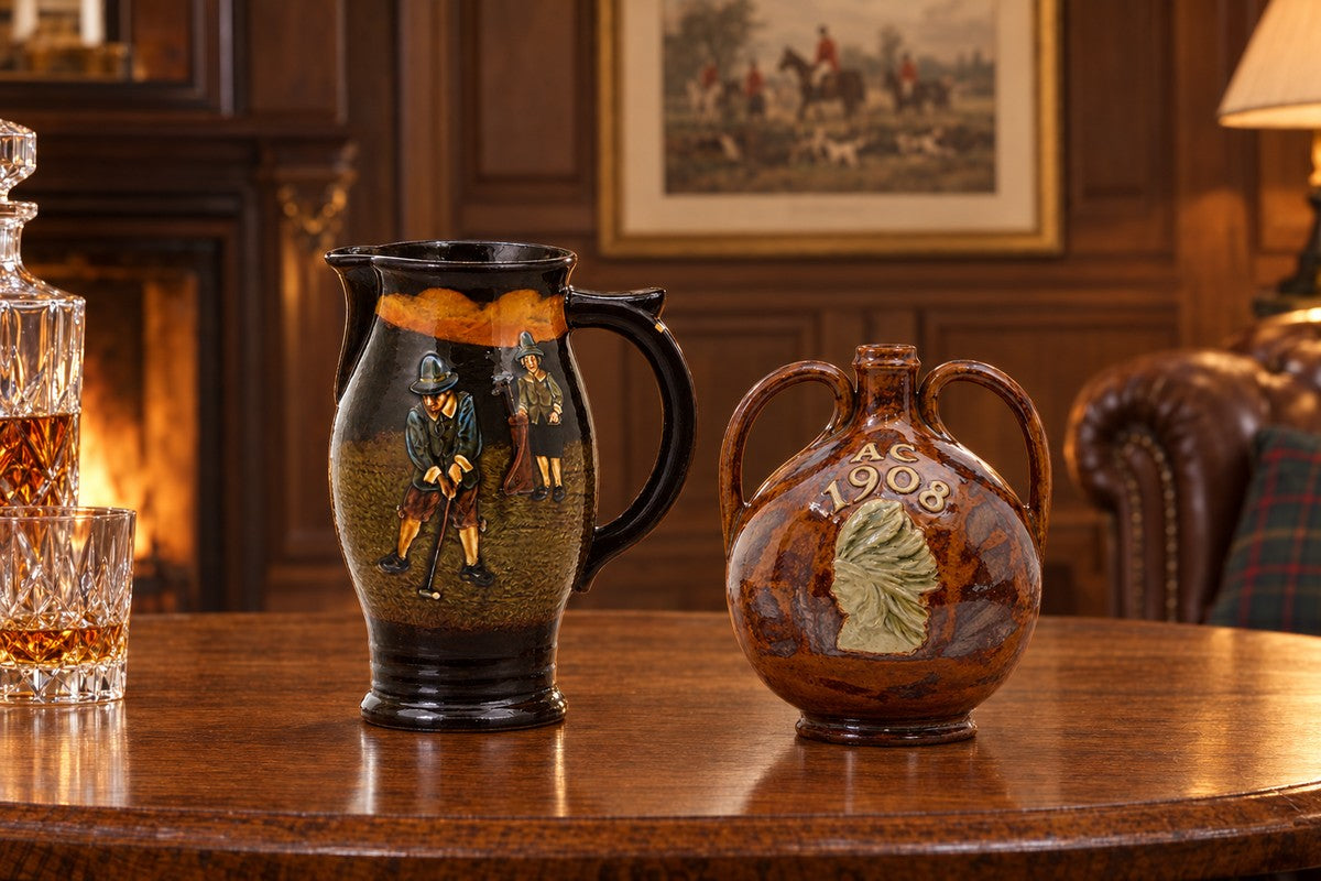 A Royal Doulton Kingsware golfers jug and an Indian Head whiskey bottle on an oak table